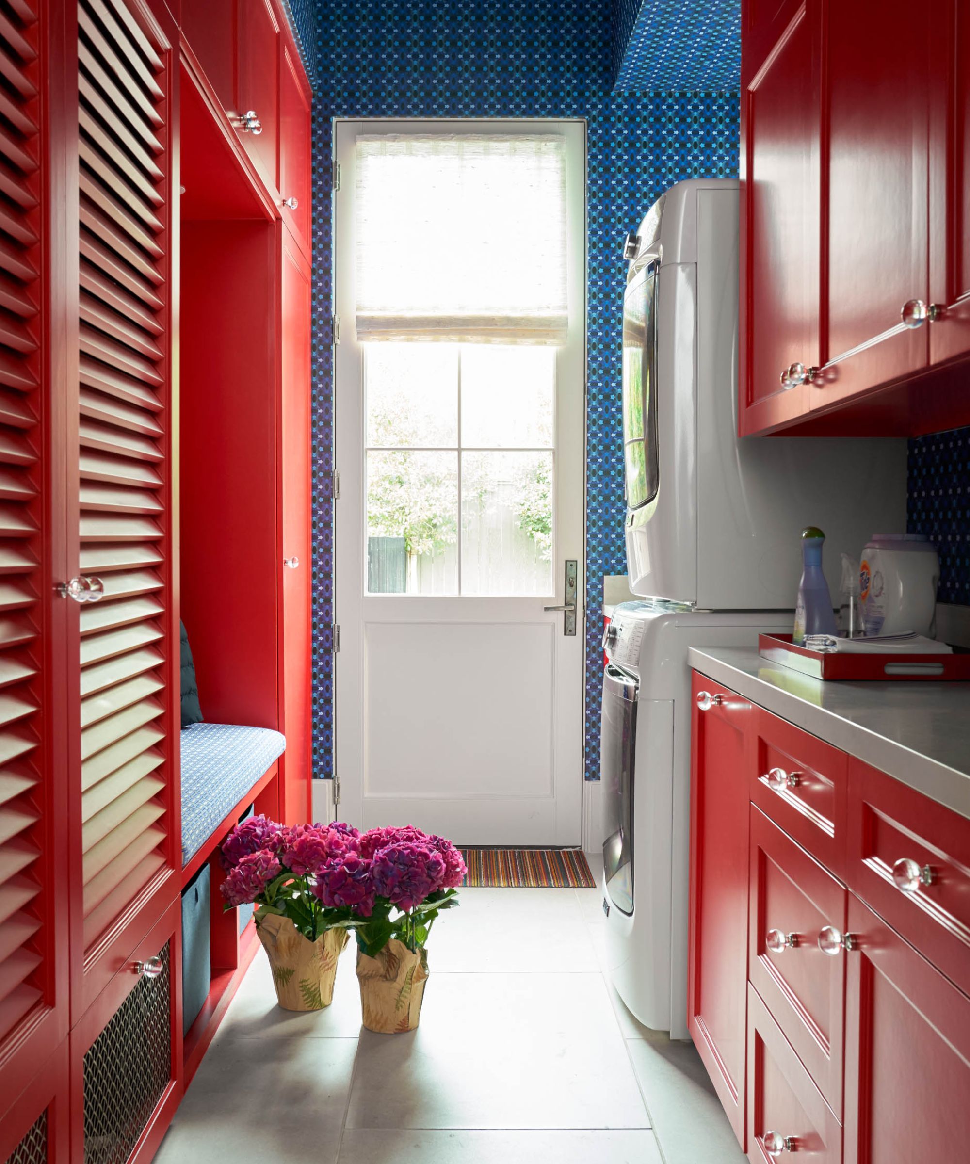 Small laundry room with red cabinets and blue wallpaper