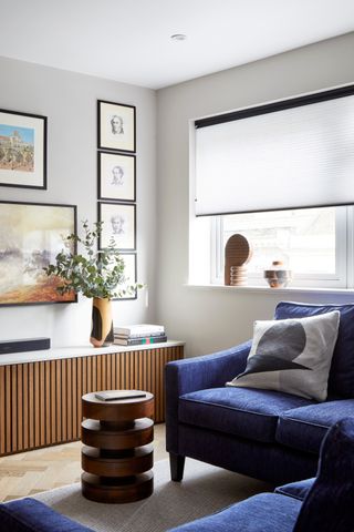 Small living room with blue velvet sofas and gallery wall