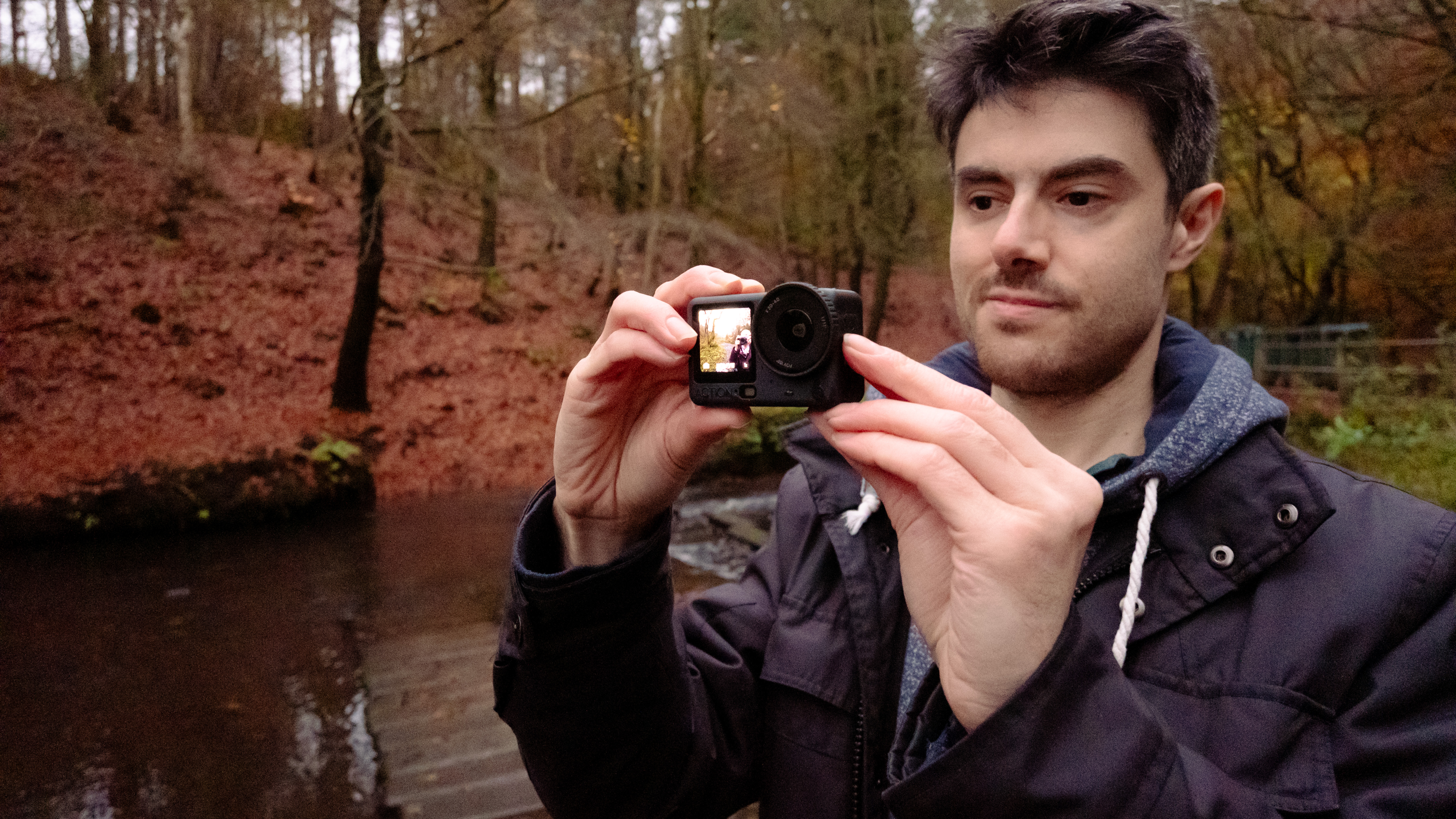 Man holding the DJI Osmo Action 6 action camera in a woodland setting