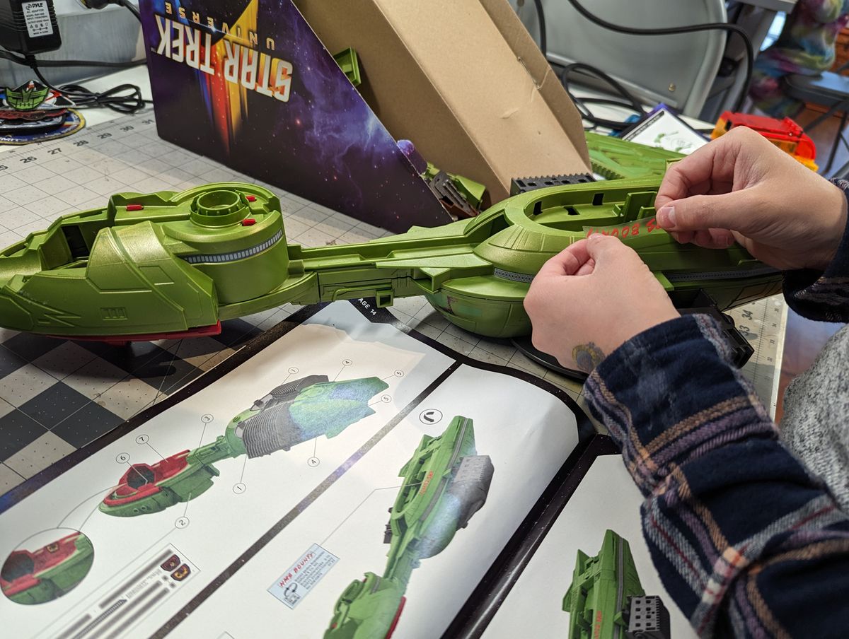 a child assembles a klingon bird of prey on a workbench