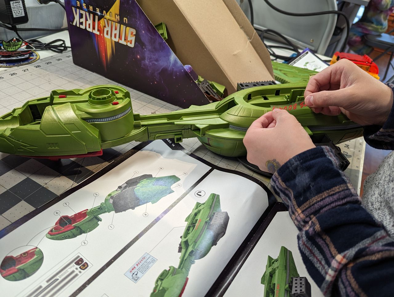 a child assembles a klingon bird of prey on a workbench