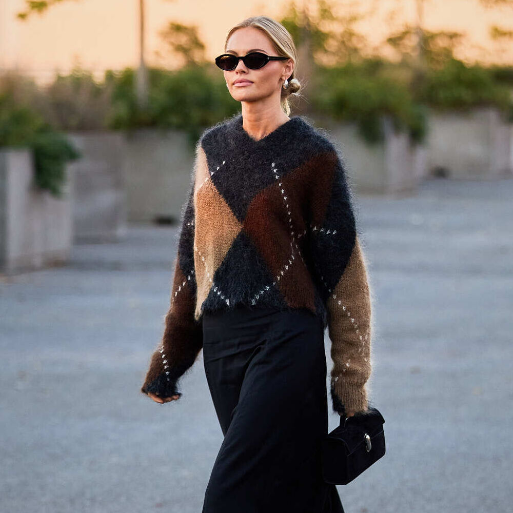 A woman attends New York fashion week wearing a mohair argyle sweater in grey, tan and burgundy.