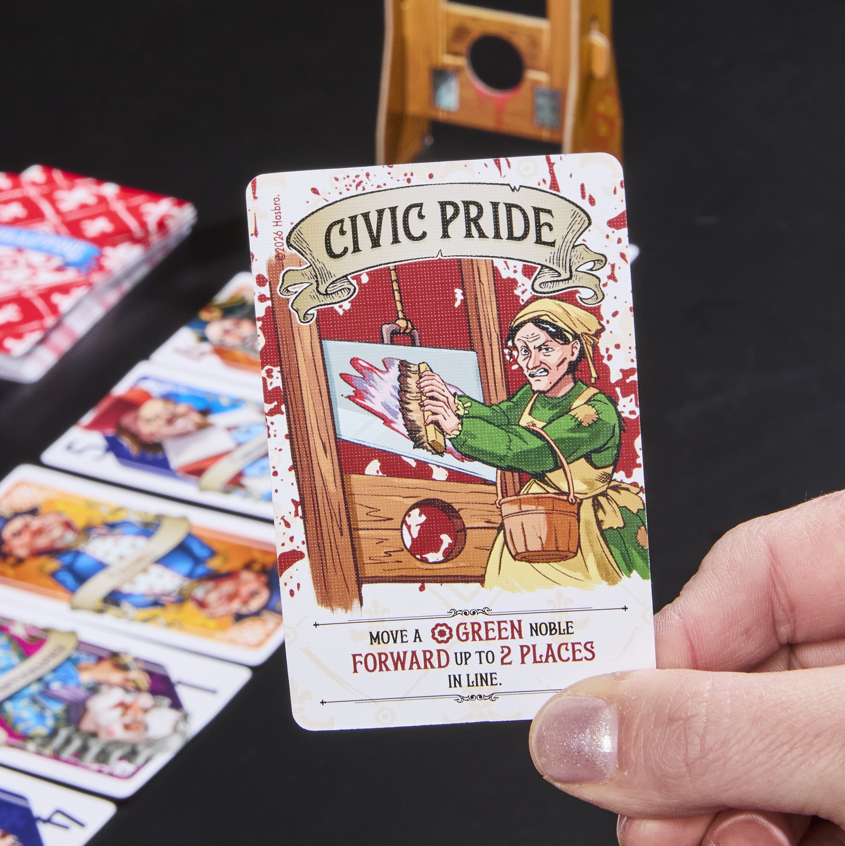 Guillotine box, cards, and prop on a dark background