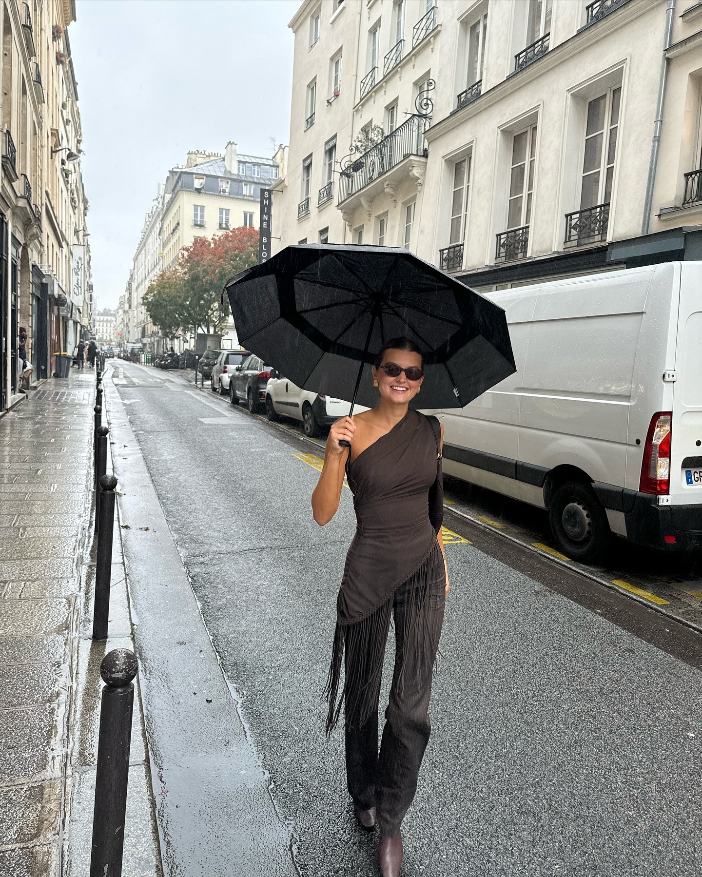Fashion person Sara wears the best square toed boots. She wears brown boots, a dark brown pinstripe trouser and dark brown top. She is smiling at the camera holding an umbrella in a recent image from her Instagram.