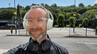 Sony WH-CH720N headphones worn by TechRadar Editor Matthew Bolton, near a road, who has a pair of Sony WH-1000XM3 headphones around his neck too