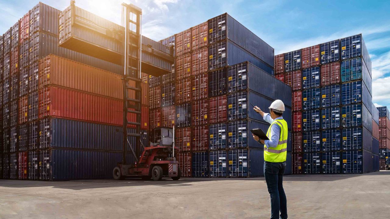 Hardhat worker pointing at shipping containers