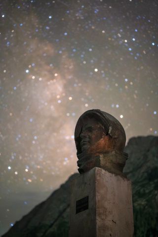 Yuri Gagarin statue with milky way behind, the sky is full of stars.