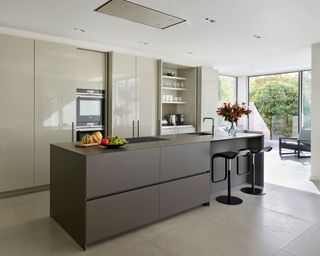 Designing a modern kitchen featuring a pale gray scheme with glossy cabinetry and a long island with bar stools.