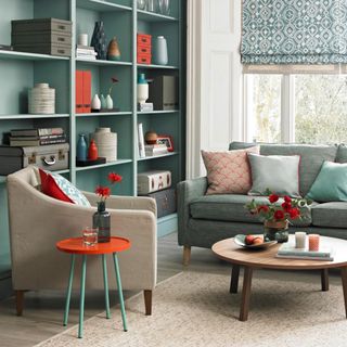 Living room with wall of blue-painted shelving and grey upholstery