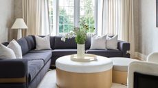 living room with large grey corner sofa and round coffee table in oak with boucle upholstered top