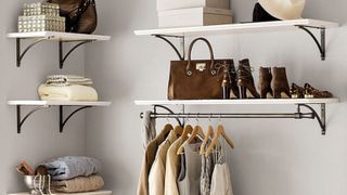 Valet Shelving with Rod in bedroom corner with shoes and handbag on top, and hanging clothes underneath