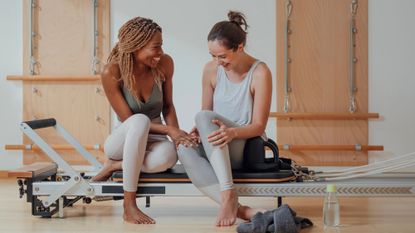 What is Pialtes? Two women sit on a Reformer Pilates machine