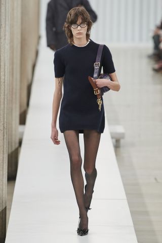 Miu Miu model in a T-shirt minidress and glasses at the fall/winter 2023 show.