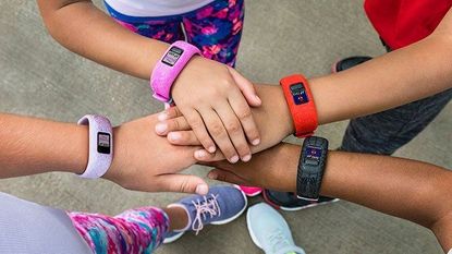 Best smartwatch for kids: Kids holding hands wearing Garmin's Vivovit Jr fitness tracker