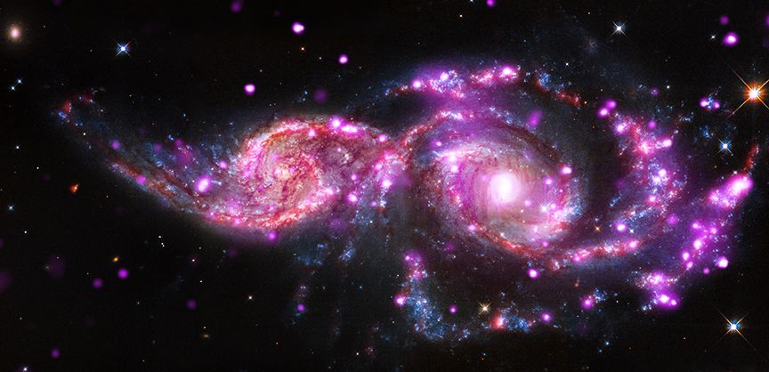 This composite image of the grazing galaxies NGC 2207 and IC 2163 contains data from NASA&#039;s Chandra, Hubble and Spitzer space telescopes. (Chandra data shows up as pink, Hubble data as red, green and blue, and Spitzer data as red.)