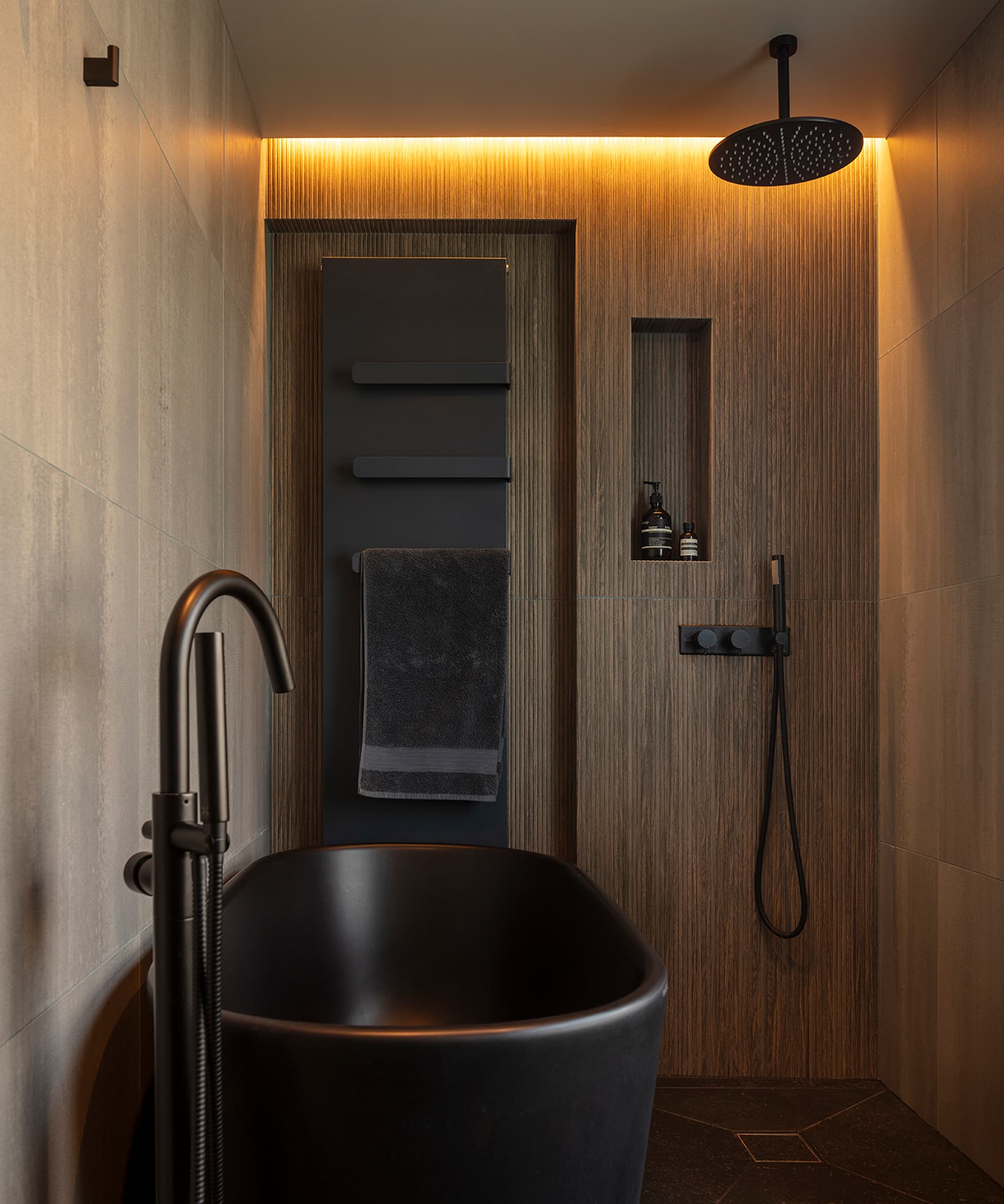 A bathroom with a black bath and overhead shower