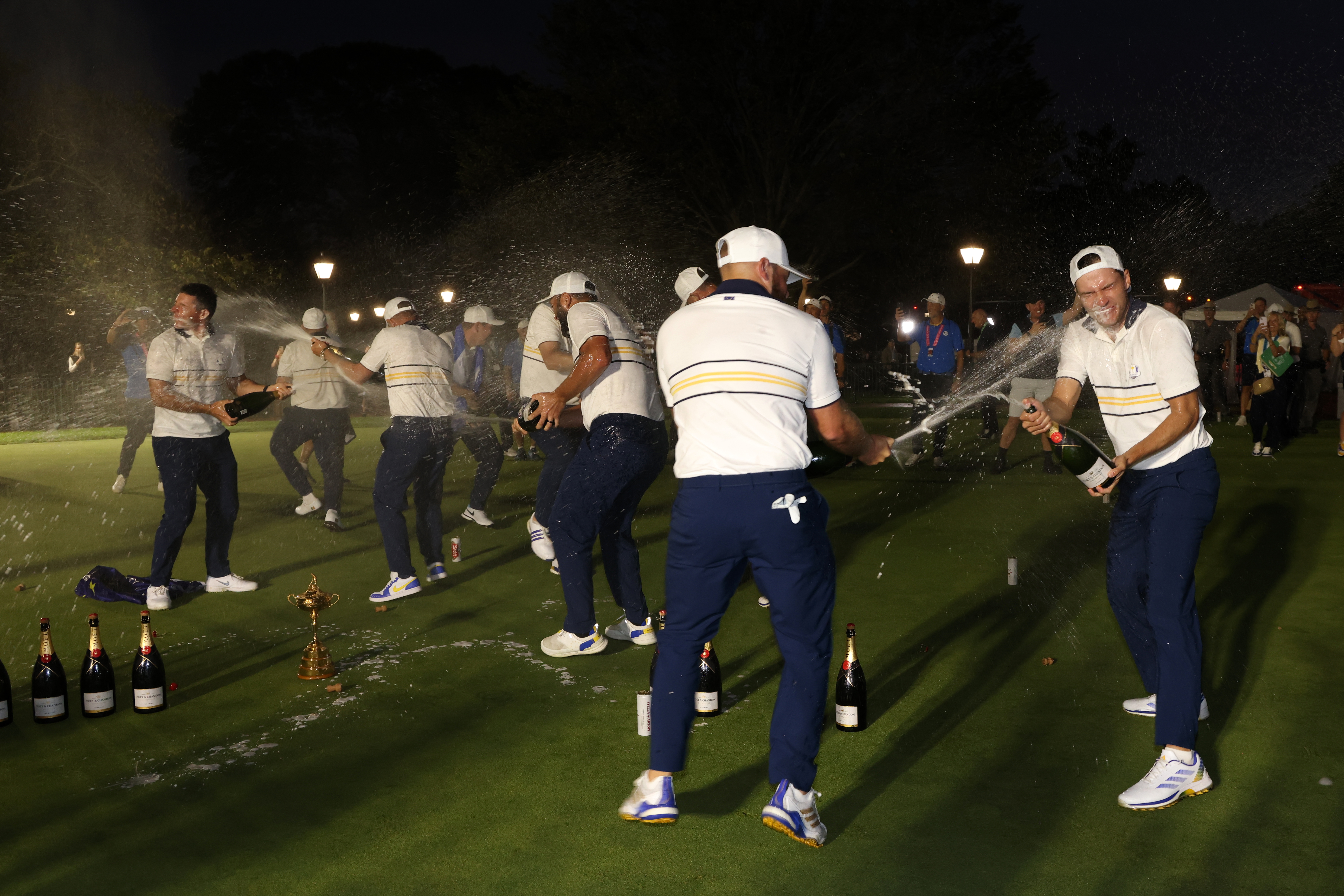 Team Europe spray each other with champagne in the dark at Bethpage State Park