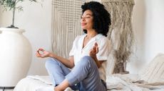 Woman doing peaceful meditative yoga pose on bed first thing in the morning