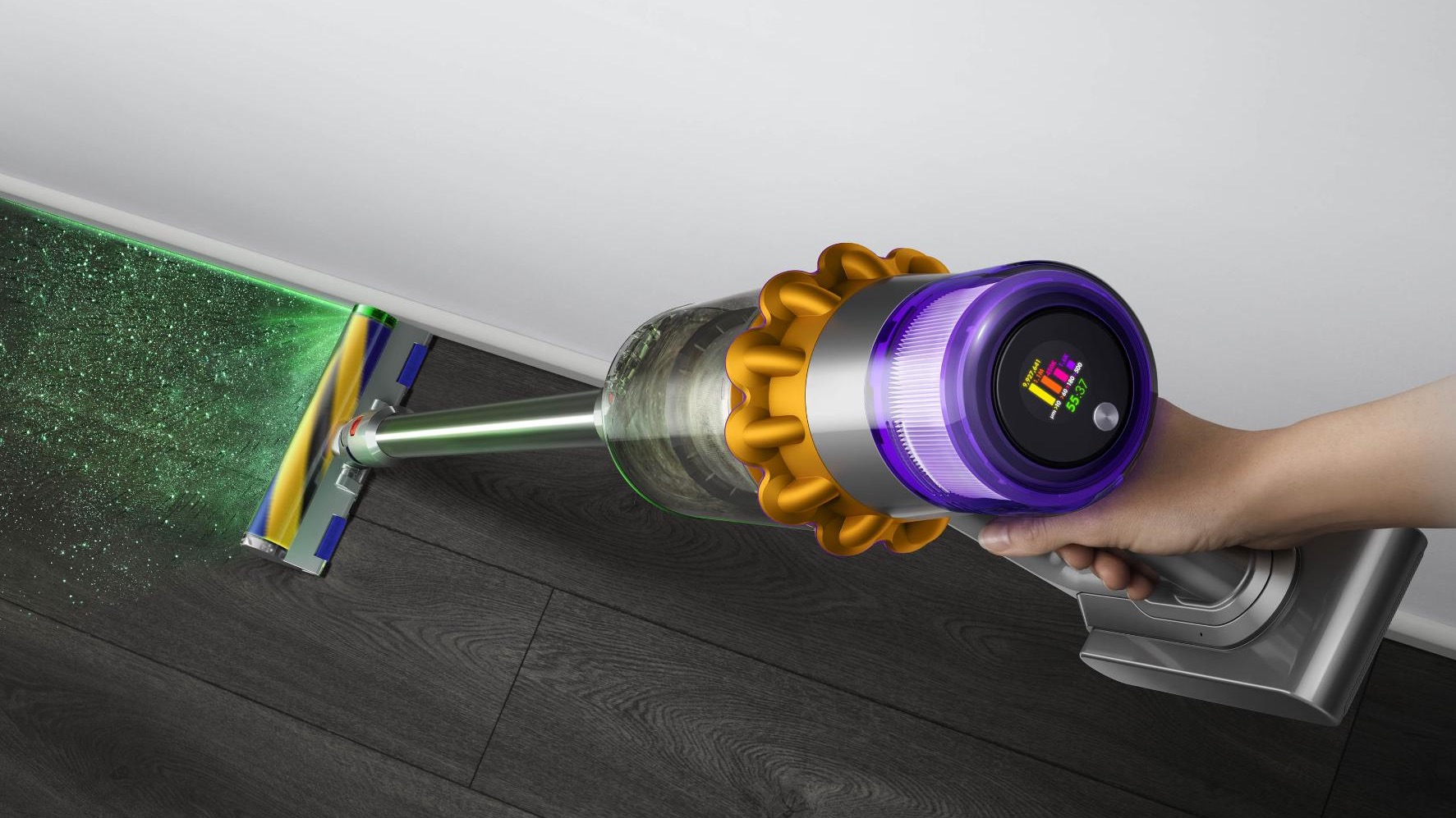 A hand holding the Dyson V15 Detect with the laser light on on the Laser Fluffy cleaning head