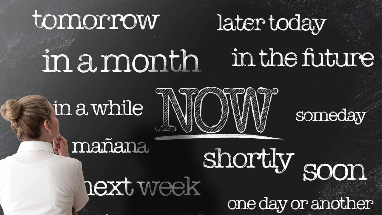 A woman stands in front of a blackboard with the words &amp;quot;tomorrow,&amp;quot; &amp;quot;later today&amp;quot; and &amp;quot;NOW&amp;quot; written on it.