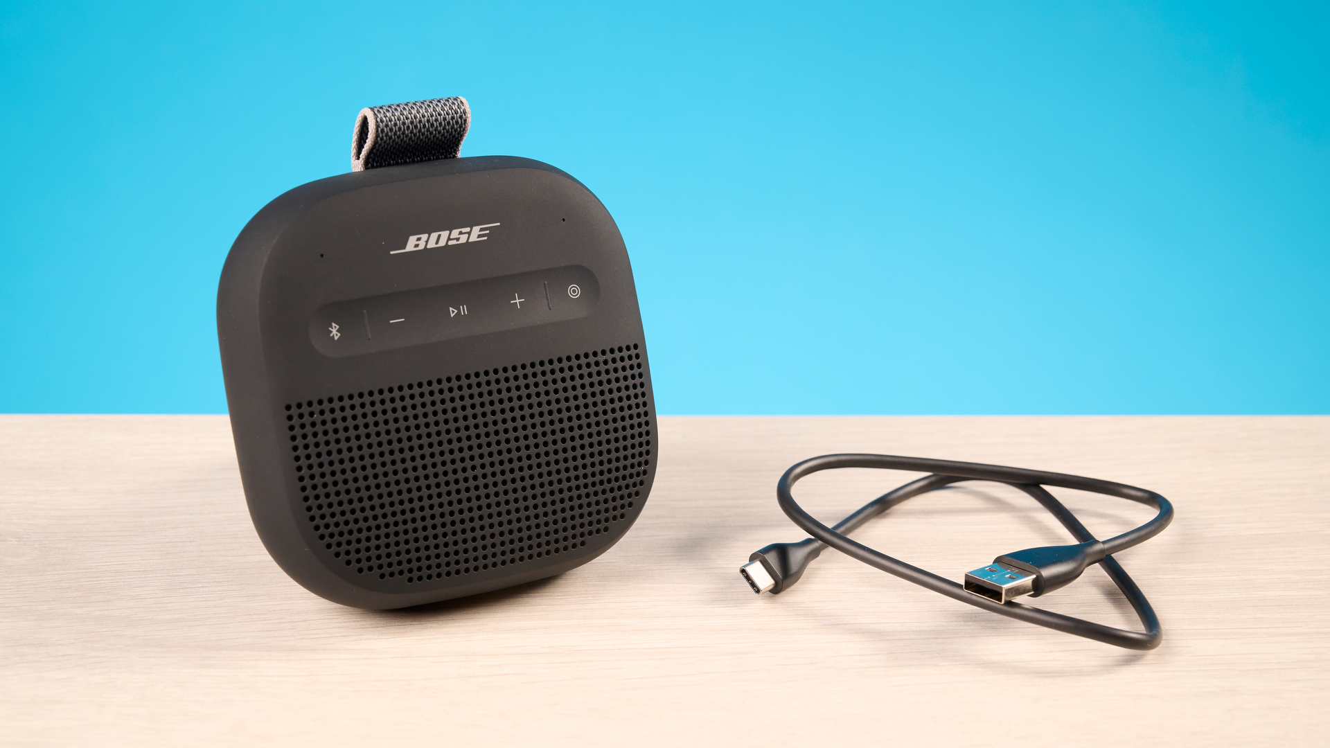 Bose SoundLink Micro 2 in black photographed in front of a blue background