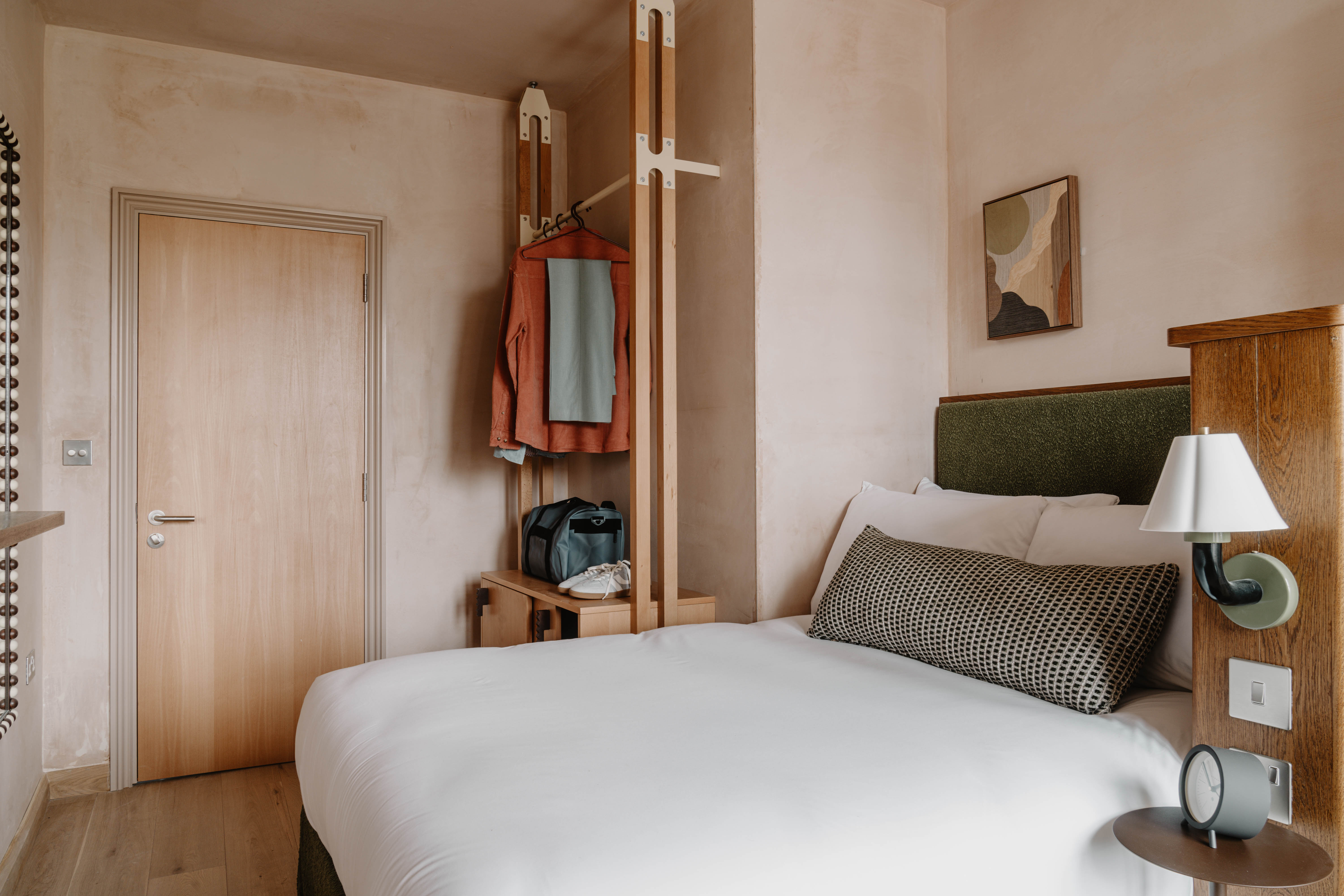 A neutrally tinted hotel with argilla-toned walls, sculptural furnishings, wooden surfaces, and curated art and tilework.