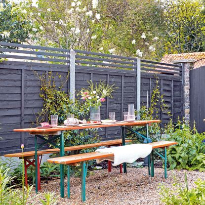 garden table with bench seating with black fence with trellis topper 