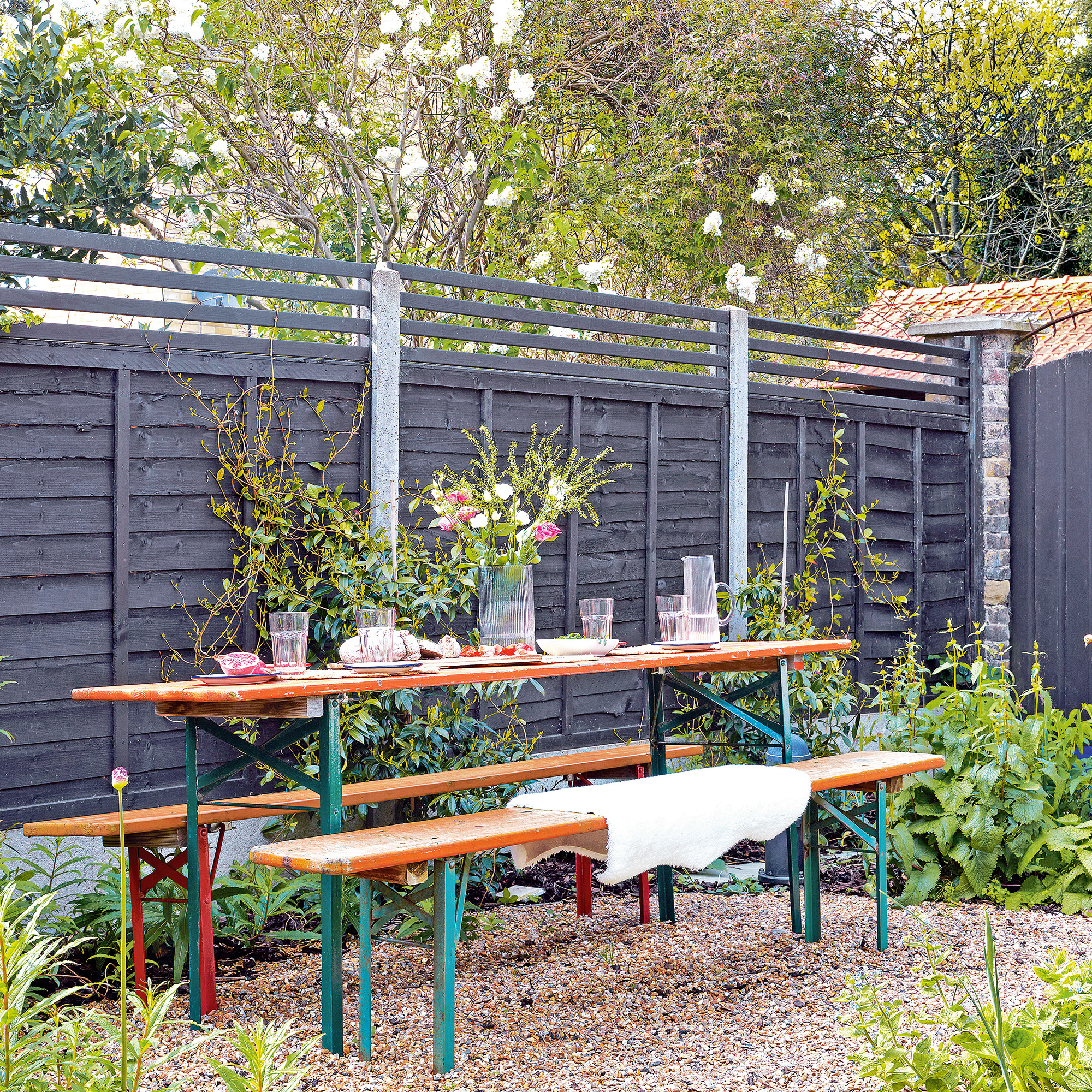 garden table with bench seating with black fence with trellis topper 