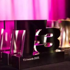 T3 Awards 2021 trophy sitting on a black surface with a pink background behind it