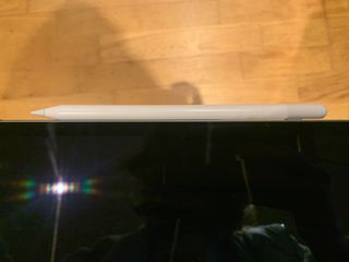 A white NovaPlus A8 Duo stylus being held in a hand and used on an iPad