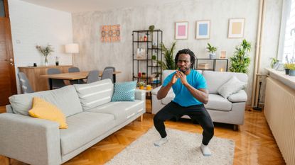 Man doing bodyweight squats in living room