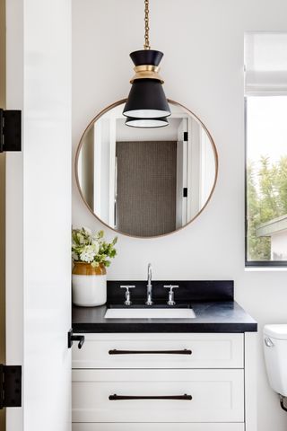 white bathroom with black pendant light, black basin top and handles