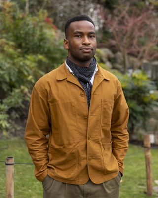 portrait of riba president muyiwa oki wearing a mustard jacket and grey scarf