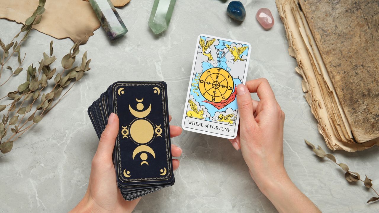 Woman with tarot cards at grey table, closeup.