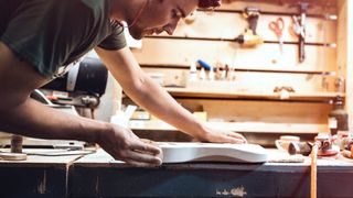 Man sands a guitar's body in his workshop