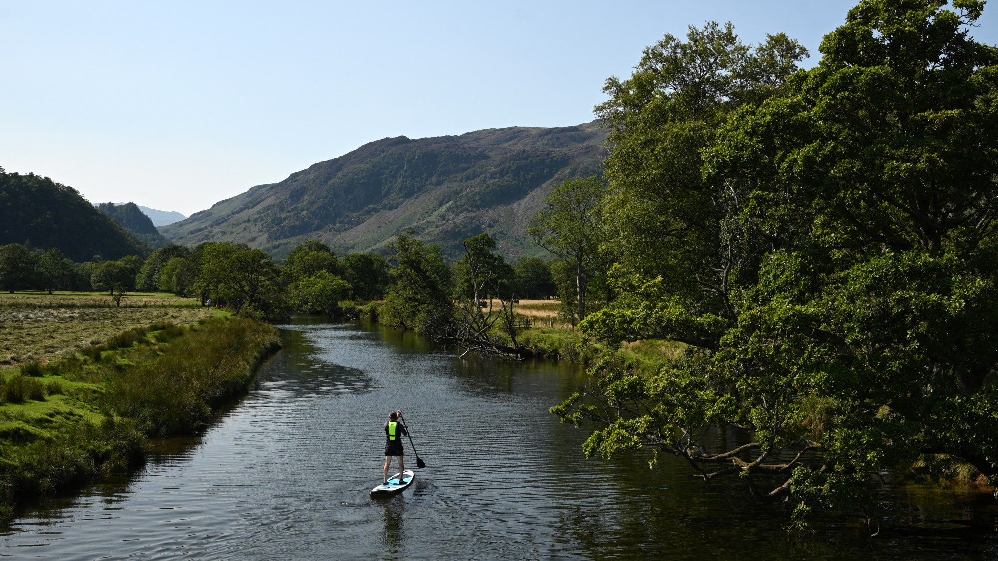 paddleboarding travelling along a river in the countryside