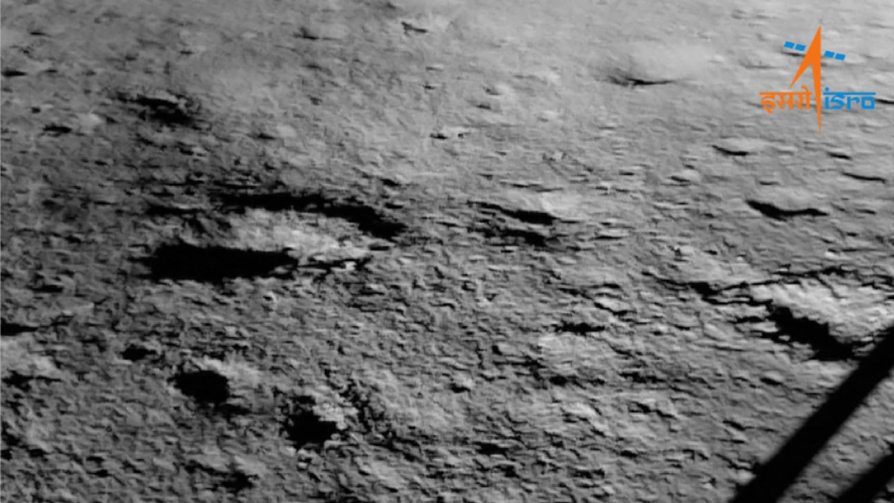 the gray surface of the moon can be seen beside the leg of a lunar lander