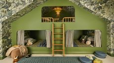 a vaulted attic room with tree wallpaper across walls and ceiling with a custom green painted triple bunk bed for kids