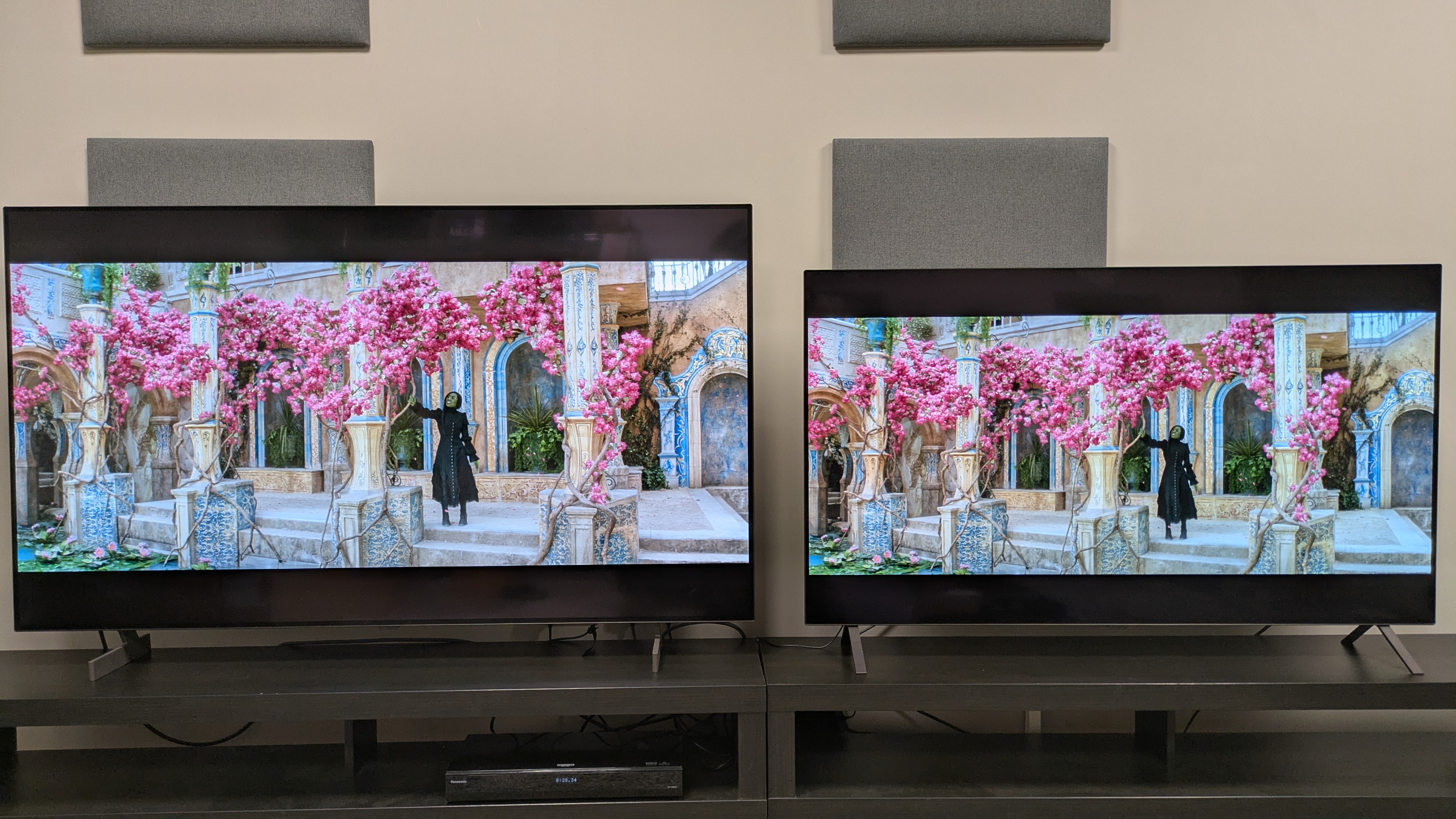 LG B6 (左) と LG B5 (右) の画面にはウィキッドが表示され、ピンクの花が咲く木の下にエルファバが立っています。どちらのテレビも優れた色再現を示していますが、B6 の色は少し大胆です。