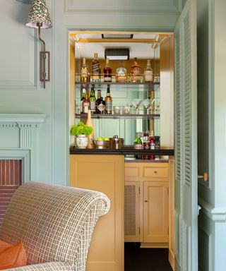 home bar in alcove cupboard with yellow cabinetry and aqua walls around it