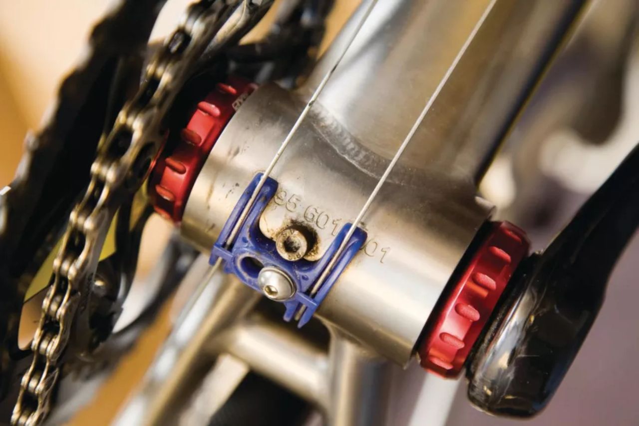 An underside view of a titanium bicycle, fitted with a red bottom bracket shell