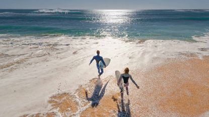 Two surfers running to the ocean