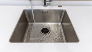 An image of a garbage disposal system located within a sink, with running water being poured down it