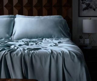 Luxome Luxury Sheet Sets in blue against a wood bed frame.