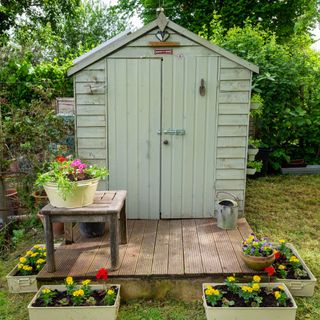 green shed in garden on decking area