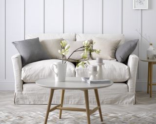 A sofa bed with off-white upholstery in a white living room