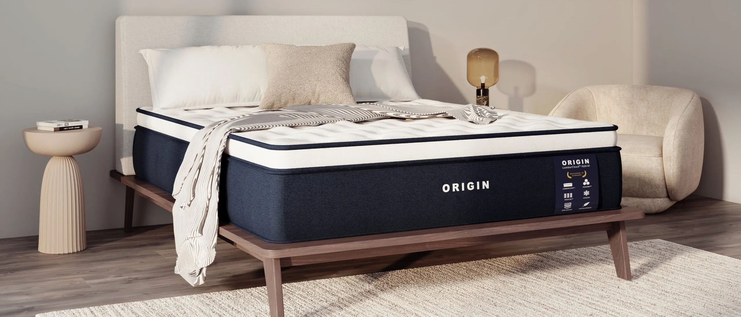 The Origin LumbarCloud Mattress on a bed frame with pillows and a throw