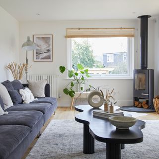 white living room with grey sofa black coffee table log burner grey rug round vase plant