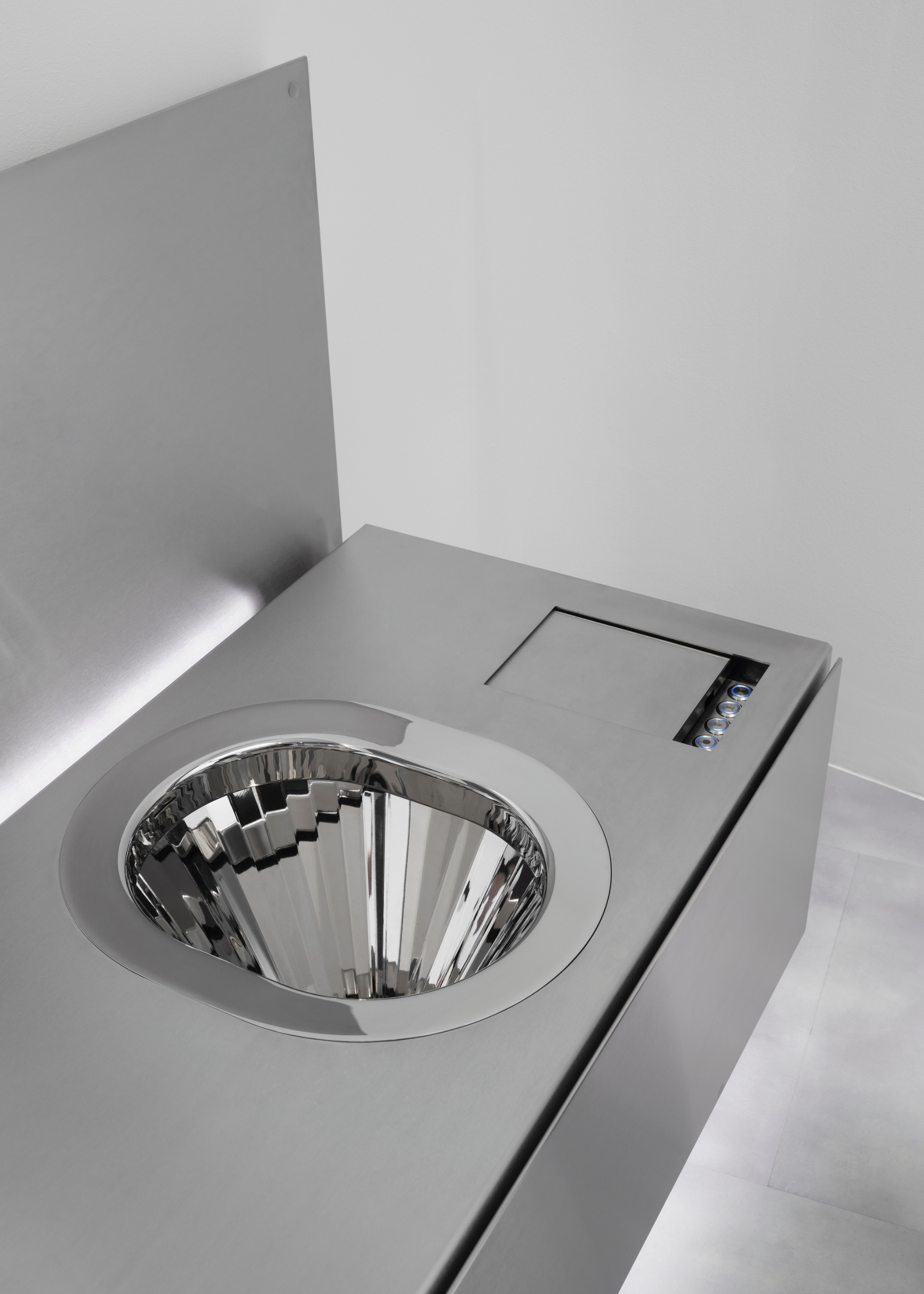 a chrome silver shallow toilet integrated into a stainless steel counter