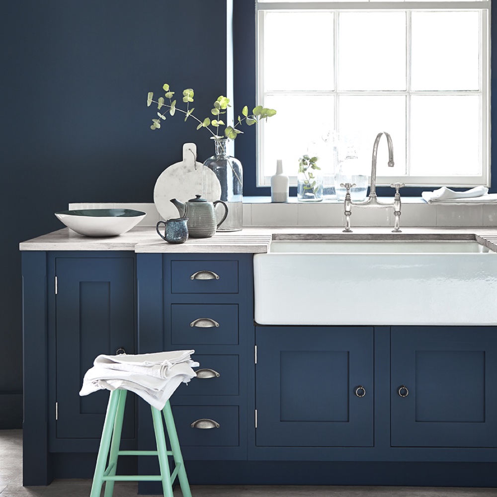 kitchen area with blue wall and blue cabinets with stool and washbasin